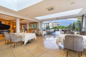 a restaurant with white tables and chairs and windows at Hotel Sonnbichl in Tirolo