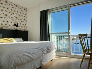 a bedroom with a bed and a large window at Logis Hotel Du Port in Plobannalec-Lesconil