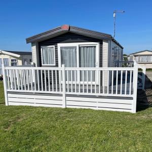 a small house with a white fence in the grass at Sun & Sand, Near Padstow, Seven Bays, Sleeps 6 in Saint Merryn