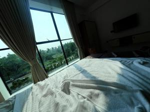 a bed in front of a window with a white blanket at Mahadeva Residency in Trivandrum
