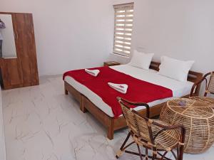 a bedroom with a bed with a red blanket and two chairs at 1BR Nest in Varkala