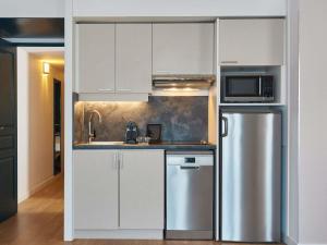 a kitchen with white cabinets and a stainless steel refrigerator at Aparthotel Adagio Monaco Palais Joséphine in Beausoleil