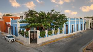a blue and white building with a tree and a car at Las Lupitas Hotel Boutique in Campeche