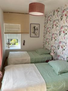 three beds in a room with flowers on the wall at le gite de sandrine in Réville