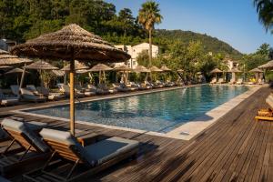 a swimming pool with chairs and umbrellas at a resort at Cook's Club Adakoy, Marmaris - Adults Only "Plus 16" in Marmaris
