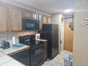 a kitchen with black appliances and wooden cabinets at Powderidge 42 2 Br: Sleeps 10 in Snowshoe