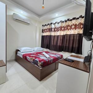 a bedroom with a bed and a desk and a television at Sumithra Palace in Bangalore
