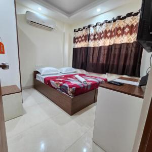 a bedroom with a bed and a desk and a curtain at Sumithra Palace in Bangalore