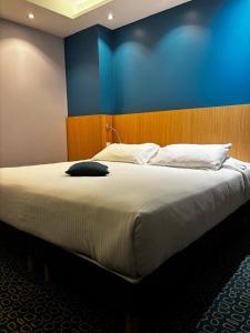 a bedroom with a large bed with a blue wall at Hôtel Restaurant Le Rive Gauche in Joigny