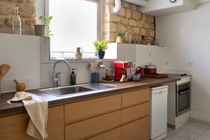 a kitchen with wooden cabinets and a sink at Le Michelet - Loft Cosy avec soirée cinéma Proche Vincennes in Montreuil