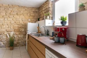 a kitchen with a sink and a brick wall at Le Michelet - Loft Cosy avec soirée cinéma Proche Vincennes in Montreuil