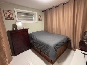 a small bedroom with a bed and a dresser at Private Bachelor Suite Near PNE in Vancouver
