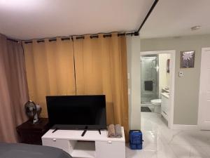 a living room with a tv and a bathroom at Private Bachelor Suite Near PNE in Vancouver