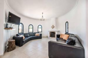 a living room with black leather furniture and a tv at Villa Vivienda Jade in Galé