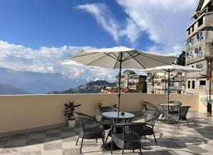 a patio with tables and chairs and an umbrella at The Boho Darjeeling Stays in Darjeeling