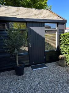 a black shed with a potted tree in front of it at Casa Dos in Hendrik-Ido-Ambacht