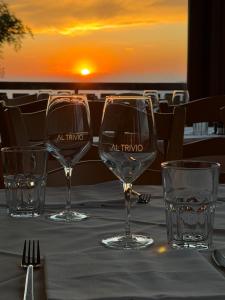 a table with three wine glasses on a table with the sunset at Hotel & Restaurant AL TRIVIO in Altana +59 photos