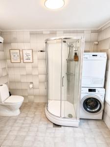 a bathroom with a shower and a washing machine at Stor attraktiv studioleilighet i sentrum in Trondheim +32 photos