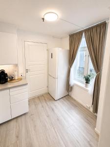 a kitchen with a refrigerator and a window at Stor attraktiv studioleilighet i sentrum in Trondheim