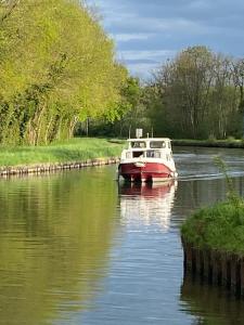 a red and white boat traveling down a river at Peniche Maryjeanne in Gannay-sur-Loire