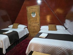 two beds in a small room with a door at Cabañas Villa Aurora in Campamento