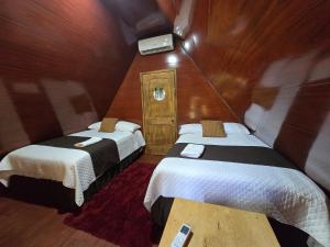 a small room with two beds and a tv at Cabañas Villa Aurora in Campamento