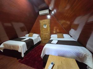 a small room with two beds and a table at Cabañas Villa Aurora in Campamento +2 photos