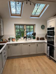 a large kitchen with white cabinets and windows at The little Hotel-luxury home in Motcombe