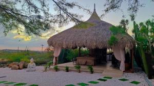a large hut with a grass roof with a table at Casita Tres Trapi in Noord