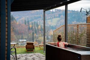 a woman sitting in a hot tub on a deck at Termalna Osada in Brenna