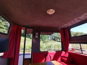 a train car with two windows with red curtains at Peniche Maryjeanne in Gannay-sur-Loire +3 photos