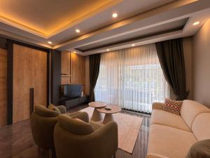 a living room with a couch and chairs and a television at Albera Villas in Kemer