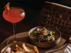 a drink next to a bowl of food and a bowl of salad at Palmar Beach Lodge in Bocas Town