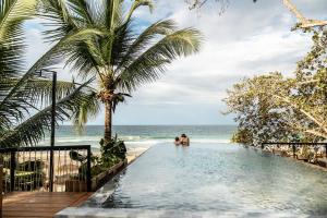a swimming pool next to a beach with palm trees at Palmar Beach Lodge in Bocas Town