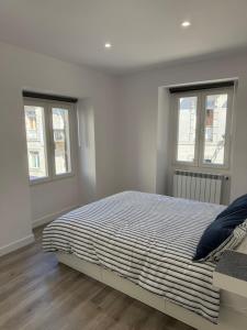 a white bedroom with a bed and two windows at Cabalo Holiday Inn in Tui