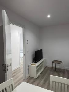 a white living room with a tv and a table at Cabalo Holiday Inn in Tui