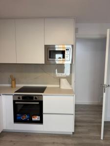 a kitchen with white cabinets and a microwave at Cabalo Holiday Inn in Tui