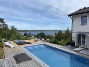 a swimming pool on a deck next to a house at Beautiful pool villa with stunning ocean view in Tyresö
