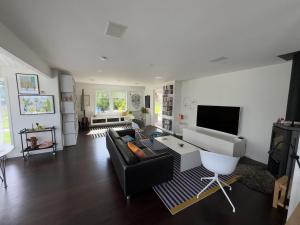 a living room with a black couch and a tv at Beautiful pool villa with stunning ocean view in Tyresö