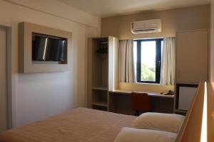 a bedroom with a bed and a desk and a window at Hotel Palace Frederico in Frederico Westphalen