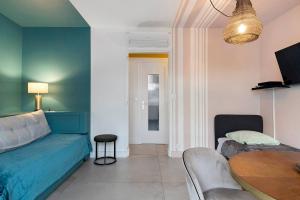 a living room with a blue bed and a table at Chez Emilien in Bordeaux