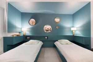 two beds in a room with blue walls and mirrors at Chez Guillaume in Bordeaux