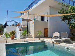 a swimming pool with two chairs and a house at Sunsets and Olive Trees in Messini