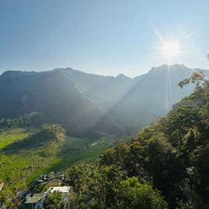 a view of a mountain with the sun shining on it at Batad Pension and Restaurant Native House in Banaue