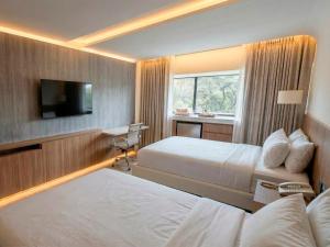 a hotel room with two beds and a flat screen tv at Viale Jardins in Foz do Iguaçu +1 photo