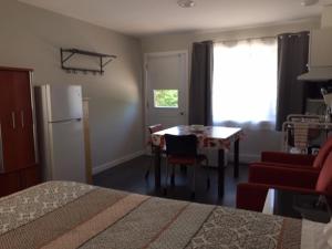 a room with a bed and a table and a refrigerator at Motel Domaine Expédition in Labelle