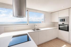 a kitchen with white cabinets and a large window at Vista Roses Mar - Ancla Mar in Roses +44 photos