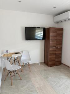a living room with a table and chairs and a television at Apartman Gold LUX in Surčin