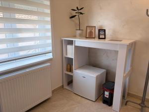 a white desk with a plant on it next to a window at Apartman Gold LUX in Surčin