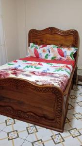 a bed with a wooden frame in a room at SKY BLUE guest house in Buea